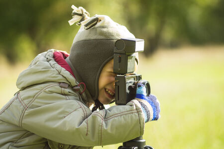 Cute small boy shooting a photography in autumn parkの写真素材
