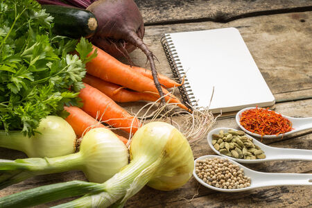Recipe background. Fresh vegetables and spices with blank page of cookbook.の写真素材