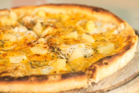 Baked cut pizza with pineapple and meat on wooden board. Selective focus image. Fast food meal timeの写真素材