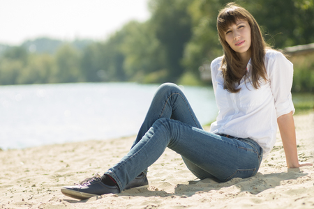 Young beautiful woman resting at the beach in summer midday.  Hipster girl lying near the water.の写真素材