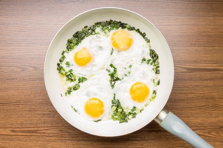 Four Fried eggs in frying pan on wood backgroundの写真素材