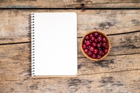 Fresh wild berries with paper notebook on wooden table. Menu background top viewの写真素材