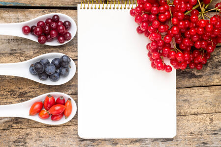 Fresh wild berries with paper notebook on wooden table. Menu background top viewの写真素材