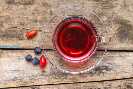 Cup of red tea with wild berries on wood background. Top viewの写真素材