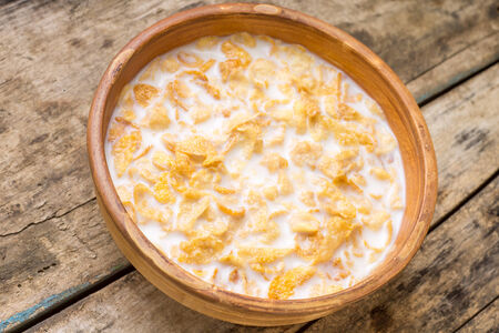 Healthy food background. Corn flakes with milk in clay bowl on wooden table