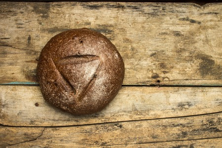 Bakery background. Loaf of bread lying on weathered wooden table.の写真素材