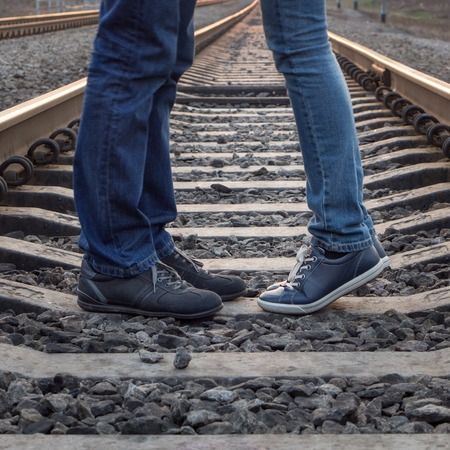 Young couple kissing at railways rails. Two people standing in love at summer dayの写真素材