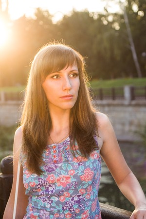 Young adult girl dreaming in sunset light. Caucasian woman waiting for somebody at summer eveningの写真素材