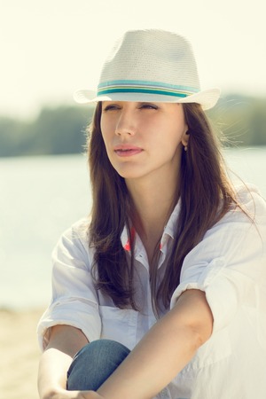 Warm color toned portrait of young woman at the beach. Pretty girl on summer vacationの写真素材