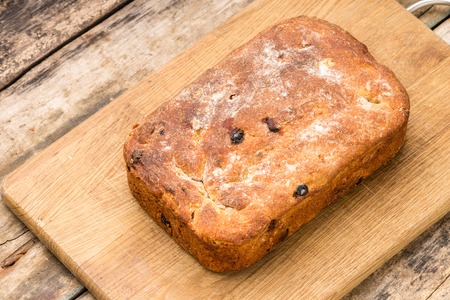 Loaf of sweet bread with raisins on cutting board. Homemade cuisine