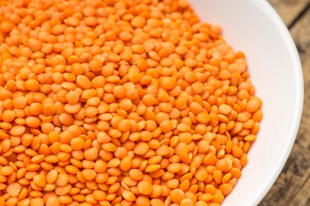 Raw orange lentil in white bowl. Vegetarian food background