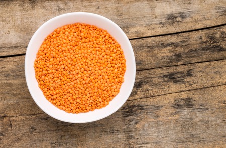 Raw lentil in bowl on wooden background. Healthy vegetarian eating background