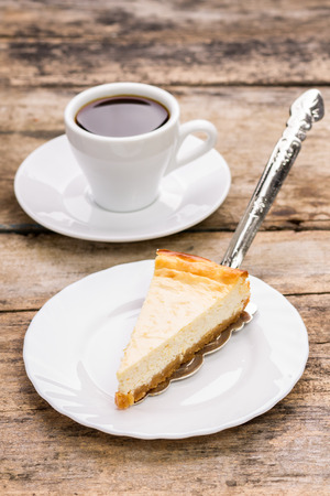 Slice of cheesecake on plate with cup of coffee on wooden table. Restaurant dessert menu backgroundの写真素材