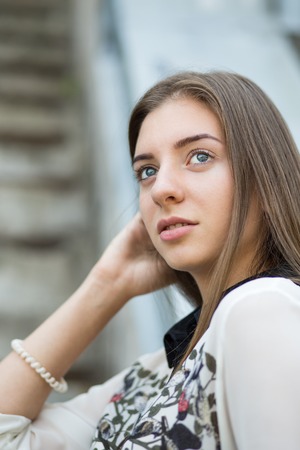 Young student hipster girl looks straight ahead. Portrait of pretty girl with long brown hair