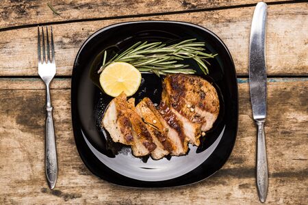 Top view image of sliced grill beefsteak served with lemon and rosemary on wooden table. Restaurant steak house menu or recipe backgroundの写真素材