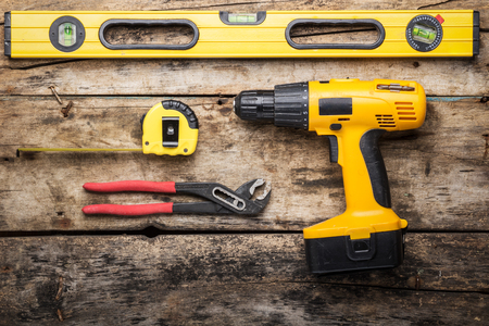 Construction tools on wooden background. Level, screwdriver or drill, tape and spanner top view imageの写真素材