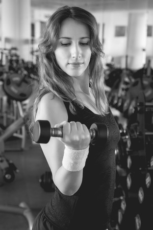 Beautiful young woman working out with weights. Attractive girl with dumbbells in a gymの写真素材