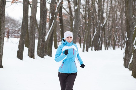Young slim woman jogging in winter park. Running caucasian girl in sportswearの写真素材