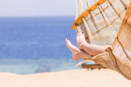 Young woman resting in hammock near the sea or ocean. Travelling beach vacation background with copy...