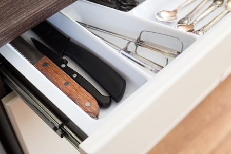 Spoons, forks and knives in cutlery box drawer in kitchen cupboard.の写真素材