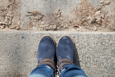 Pair of winter boots on female legs on stairs. Top view imageの写真素材