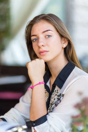 Young beautiful girl with long hair sitting in cafe. Fashion girl in the restaurant