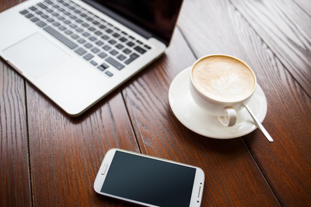 Mockup image with laptop, coffee and phone in cafe. Coffee break business backgroundの写真素材