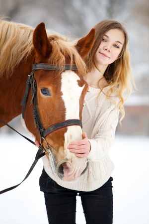 Young teenage girl with horse in winter parkの写真素材