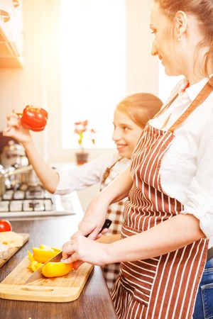 Teenage girl with her mom having fun at cookingの写真素材