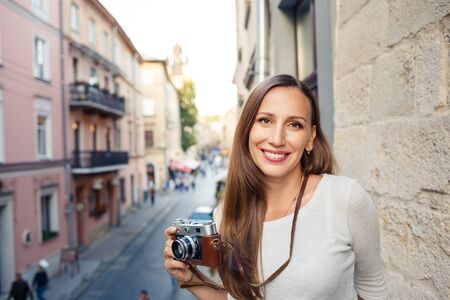Young woman standing with camera at the balconyの写真素材