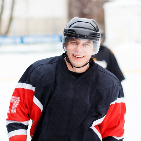 Young smiling ice hockey player in helmet and gear