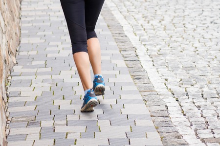 Running woman legs on cobbled road or street