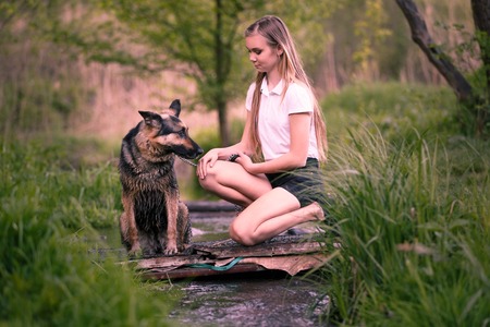 Teenage girl with her dog sitting near the creekの写真素材