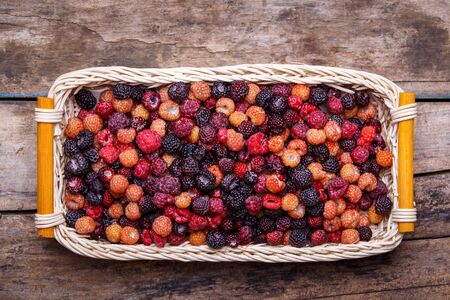 Top view of wild berries in wicker basket on woodの写真素材