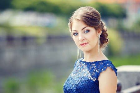 Young girl in blue dress standing near embankmentの写真素材