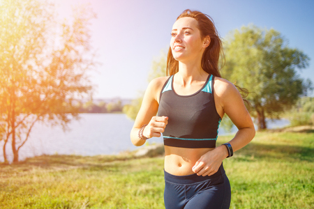 Young smiling sporty woman running in park in the morning.の写真素材