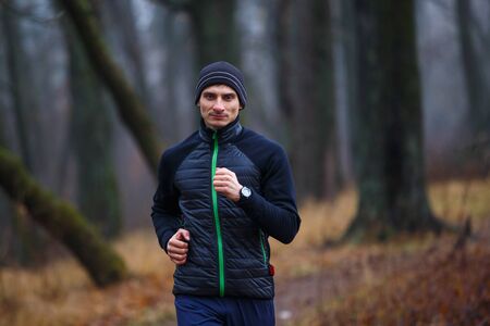 Portrait of young running man in autumn park