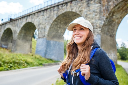 Young happy woman traveling with backpack in europe countryside. Travel concept image with copy spaceの写真素材