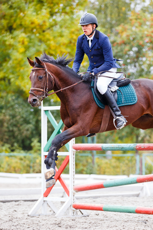 Young rider man jumping on equestrian competitionの写真素材