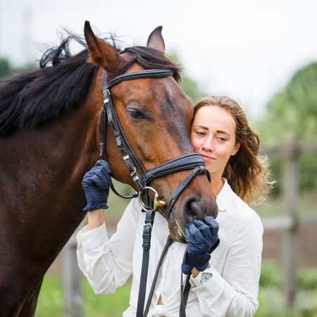 Young happy rider woman with her bay horseの写真素材
