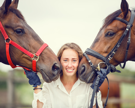 Young rider girl having fun with two her horsesの写真素材