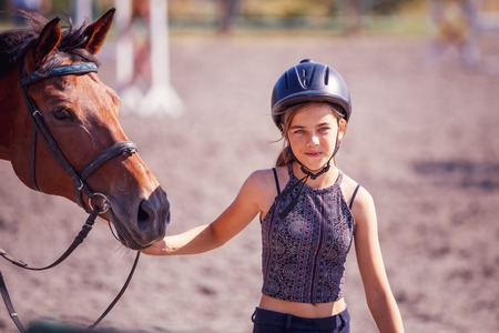 Young teenage girl with her horse at training on summer dayの写真素材