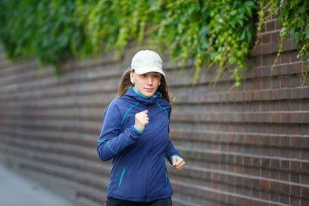 Young woman jogging along street in european cityの写真素材
