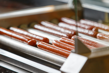 Greasy Hot dog sausages on turning cooking machineの写真素材