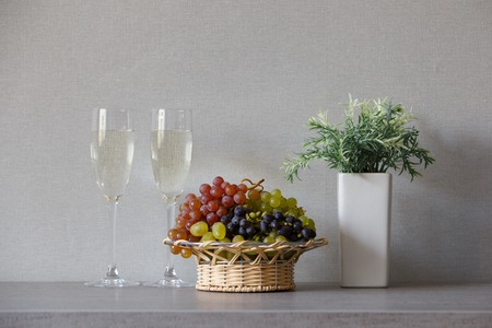 Bunches of grapes in wicker basket with white wineの写真素材