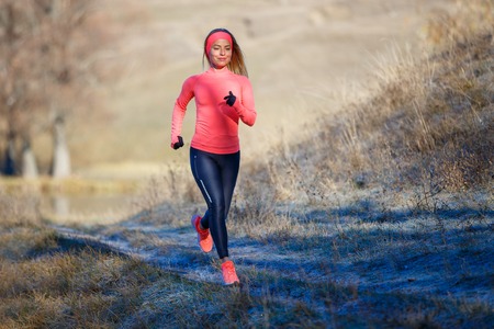 Young girl running in the park in early winterの写真素材