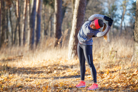 Young woman stretching before jogging in parkの写真素材