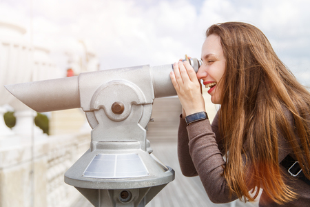 Young tourist girl watching city through telescopeの写真素材