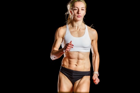 Young running athletic woman isolated on blackの写真素材