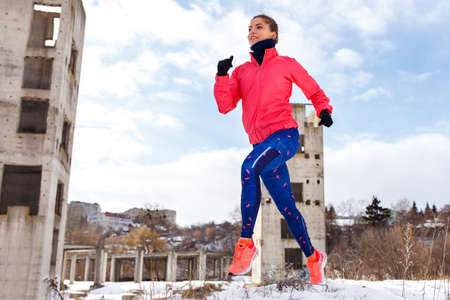 Young slim woman running outdoors in winter.の写真素材